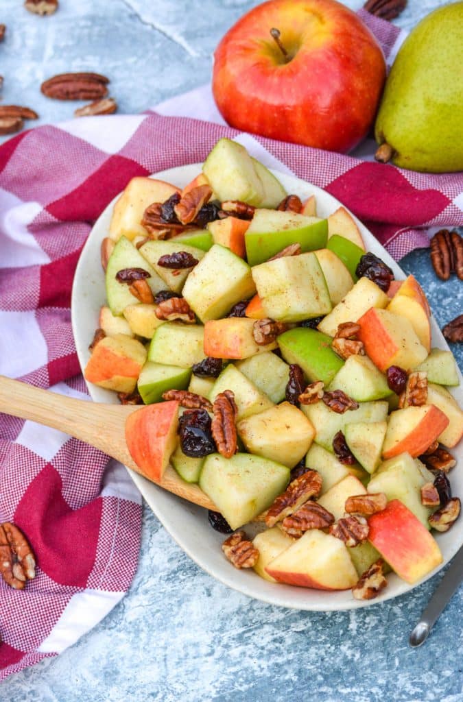 a small wooden spoon scooping a serving of fall fruit salad