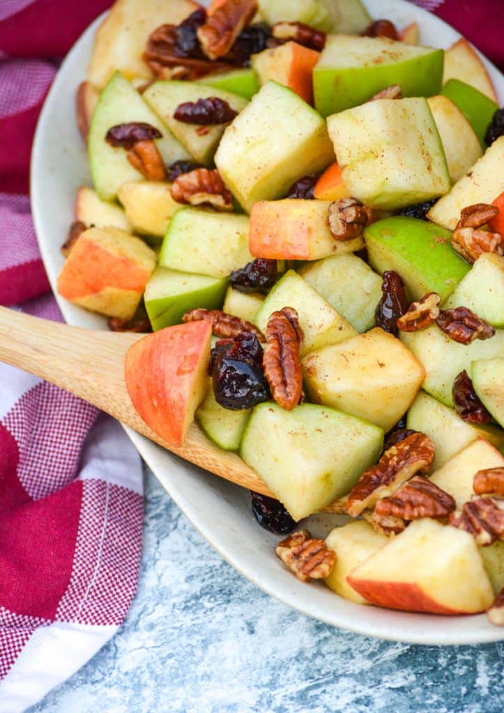 a wooden spoon stuck in a small bowl of fall fruit salad