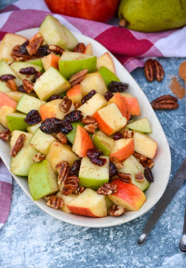 Fall fruit salad topped with raisins and ground cinnamon served in a shallow oval dish