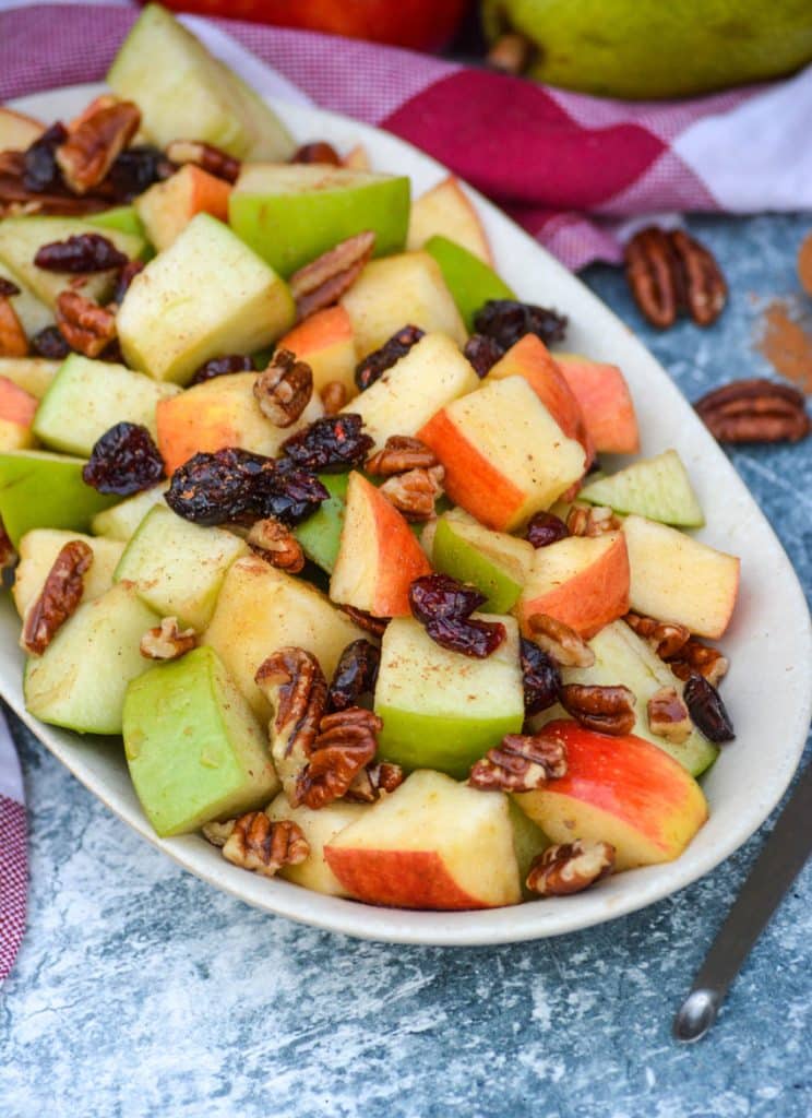 Fall fruit salad with dried cranberries and pecans served in a shallow oval shaped bowl