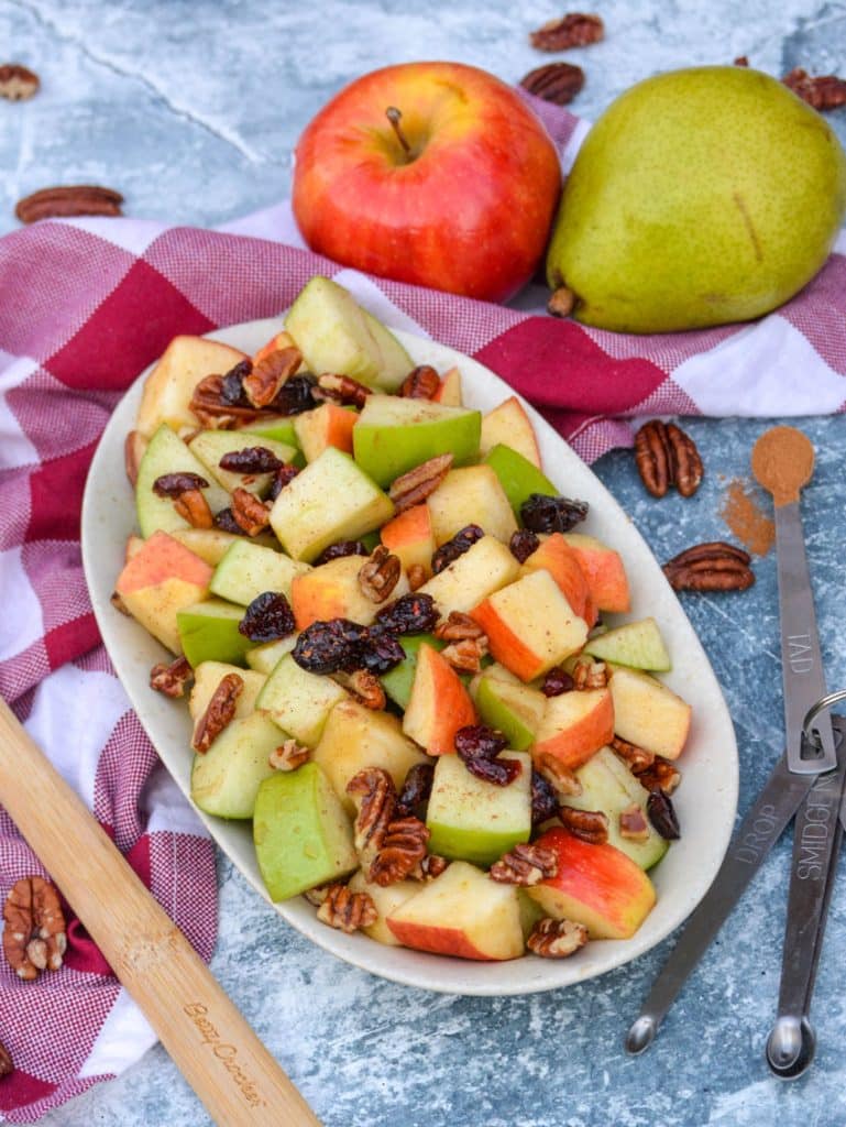 Fall fruit salad with dried cranberries and pecans served in a shallow oval shaped bowl