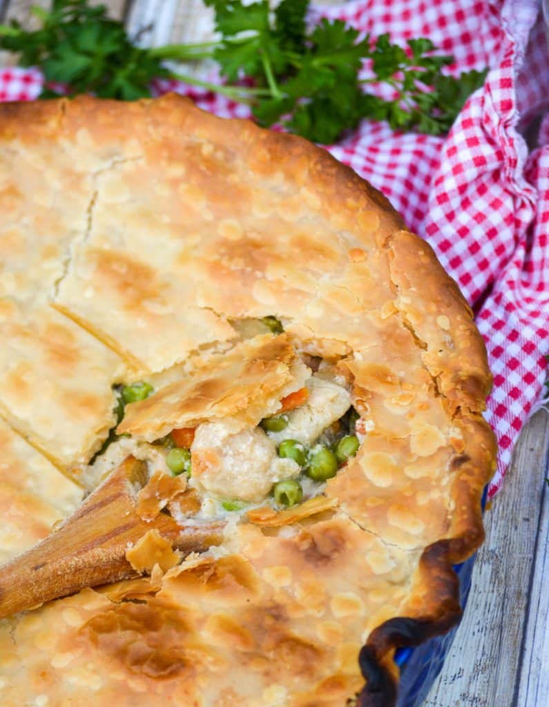 a wooden spoon scooping out the creamy center of shortcut chicken pot pie