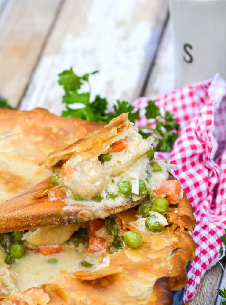 a wooden spoon scooping out the creamy center of shortcut chicken pot pie
