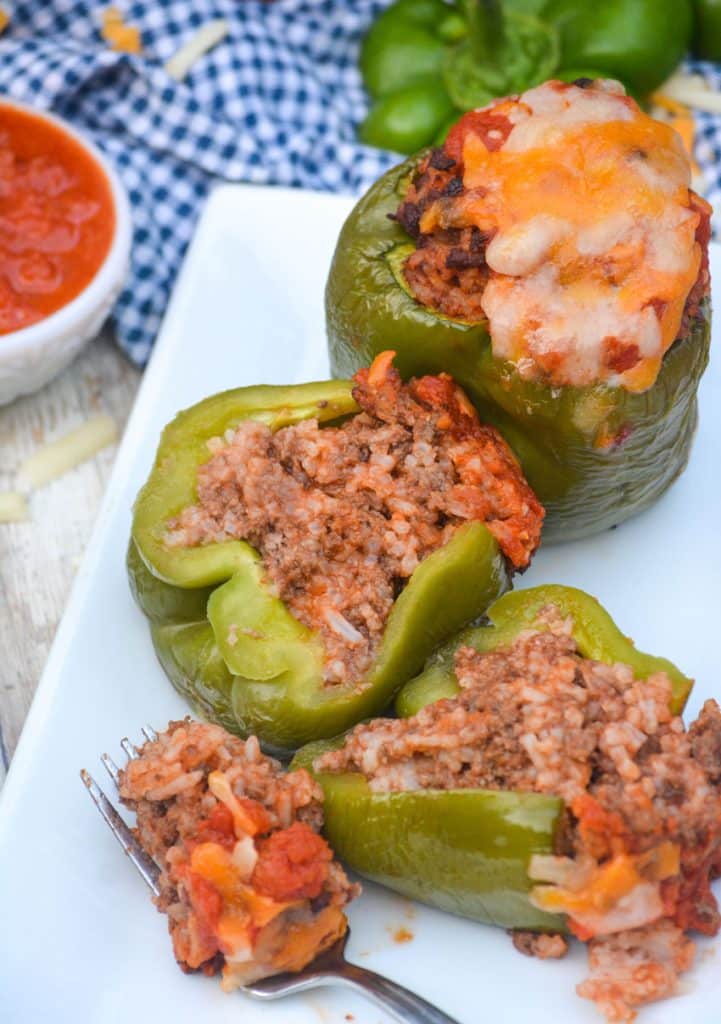 stuffed green peppers cut in half to reveal the filling inside and arranged on a white platter