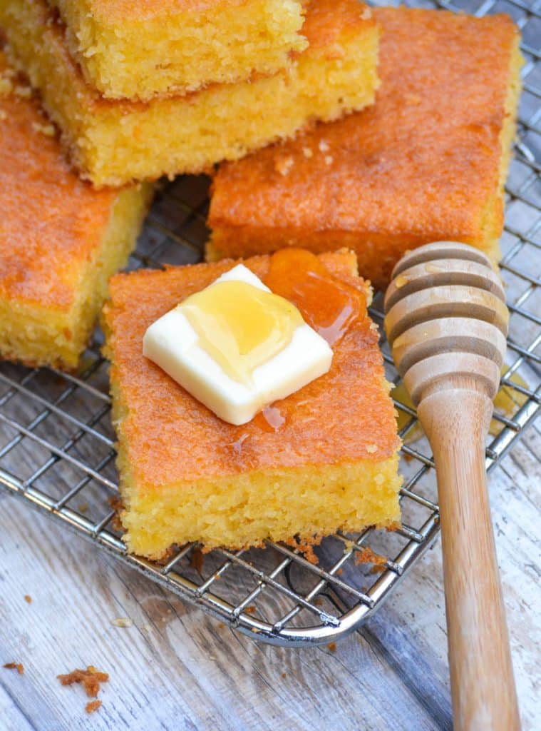 a square piece of Southern style cornbread topped with a pat of butter and drizzle of honey