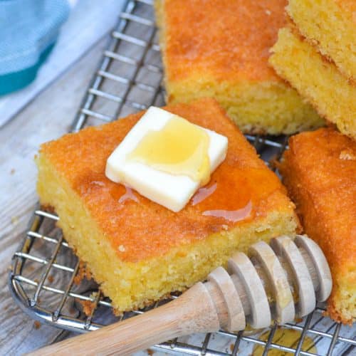 a square piece of Southern style cornbread topped with a pat of butter and drizzle of honey