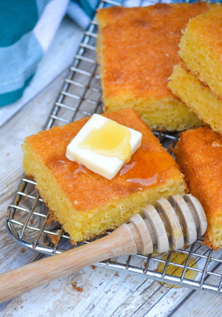 a square piece of Southern style cornbread topped with a pat of butter and drizzle of honey