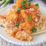 Instant pot sweet and sour chicken on a white plate with a pair of wooden chop sticks