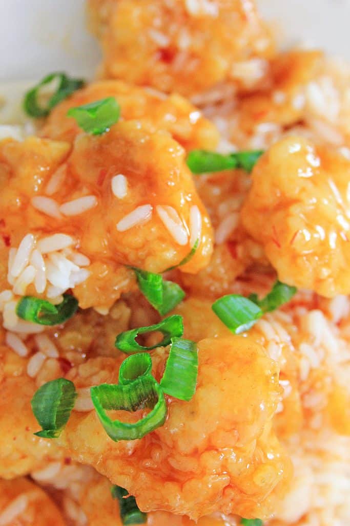 Instant pot sweet and sour chicken on a white plate with a pair of wooden chop sticks