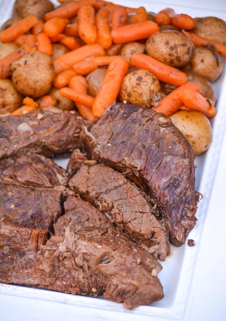 Instant Pot pot roast with carrots & potatoes arranged together on a white serving platter