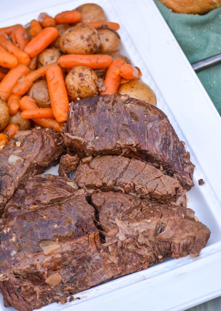 Instant Pot pot roast with carrots & potatoes arranged together on a white serving platter