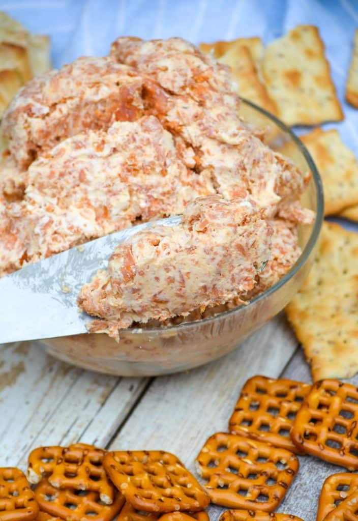a spreader scooping pepperoni cream cheese spread from a glass bowl