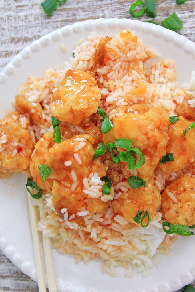 Instant pot sweet and sour chicken on a white plate with a pair of wooden chop sticks
