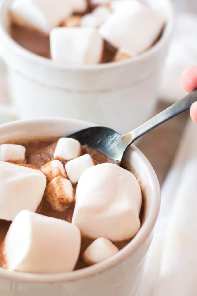 a spoon stuck in a glass of peanut butter hot chocolate