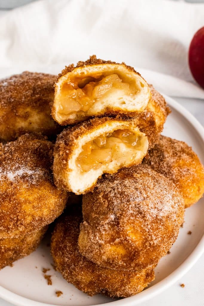 caramel apple pie bombs stacked on a white plate and opened to show the filling