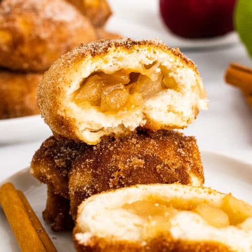 caramel apple pie bombs stacked on a white plate and opened to show the filling