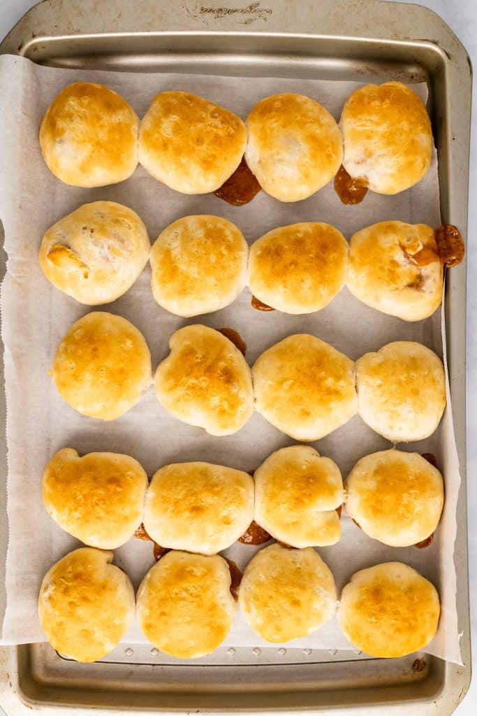 baked apple pie stuffed biscuits on a metal baking pan