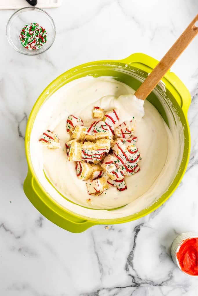 chopped christmas tree cakes on top of whipped cream in a large green mixing bowl