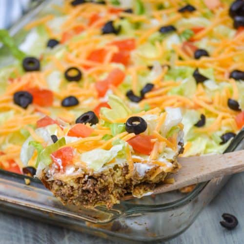 a wooden spoon holding up a scoop of baked bisquick taco casserole