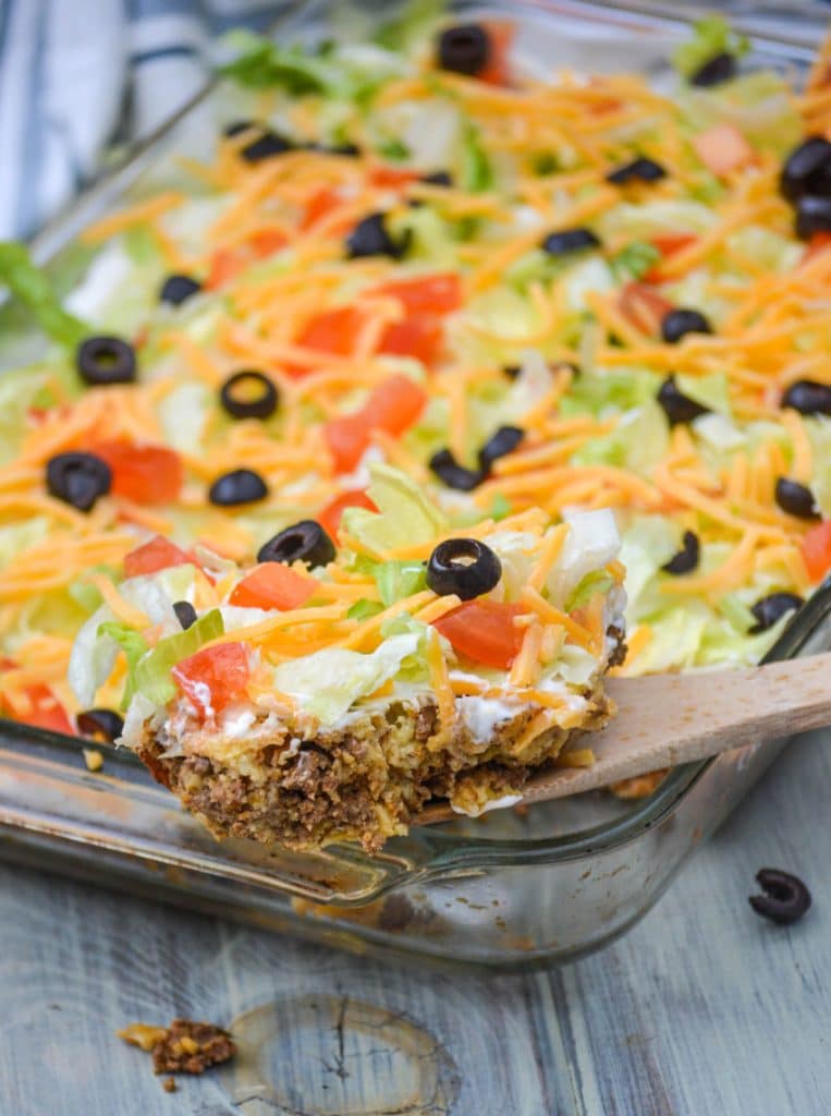a wooden spoon holding up a scoop of baked bisquick taco casserole