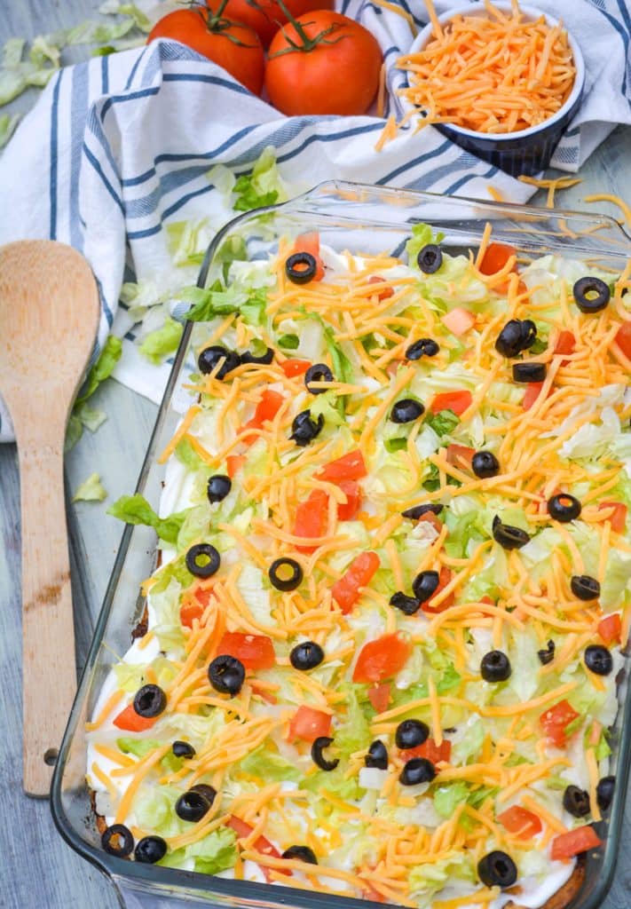 bisquick taco bake in a pyrex baking dish with a wooden spoon on the side