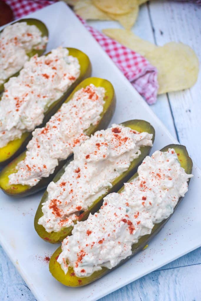 chicken salad stuffed pickle boats arranged in a row on a white serving platter