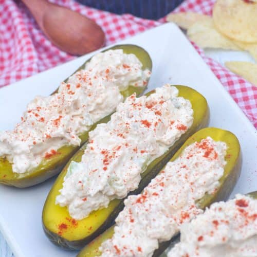 chicken salad stuffed pickle boats arranged in a row on a white serving platter
