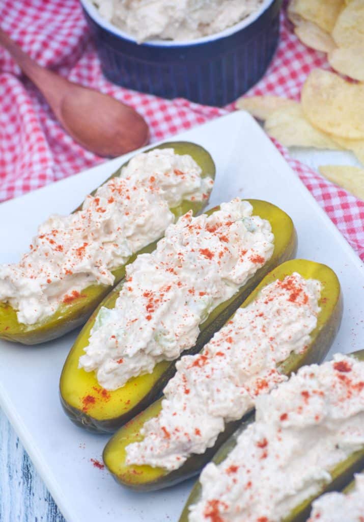 chicken salad stuffed pickle boats arranged in a row on a white serving platter