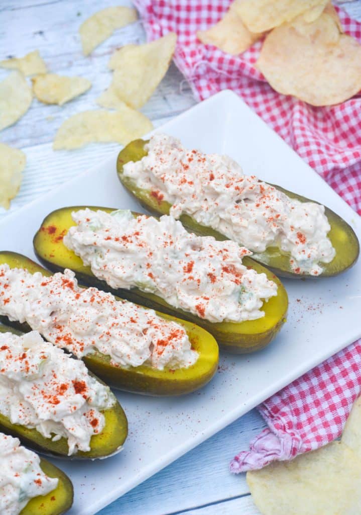 chicken salad stuffed pickle boats arranged in a row on a white serving platter