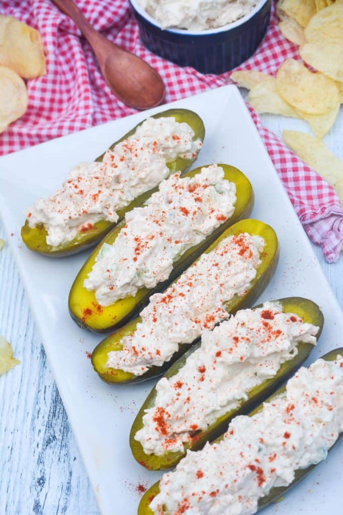chicken salad stuffed pickle boats arranged in a row on a white serving platter