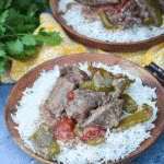 crockpot pepper steak over a bed of steamed white rice on a wooden plate