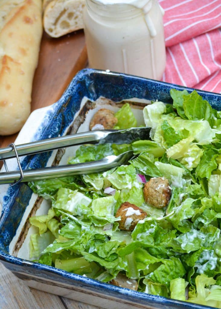 metal tongs resting on a bowl of tossed salad