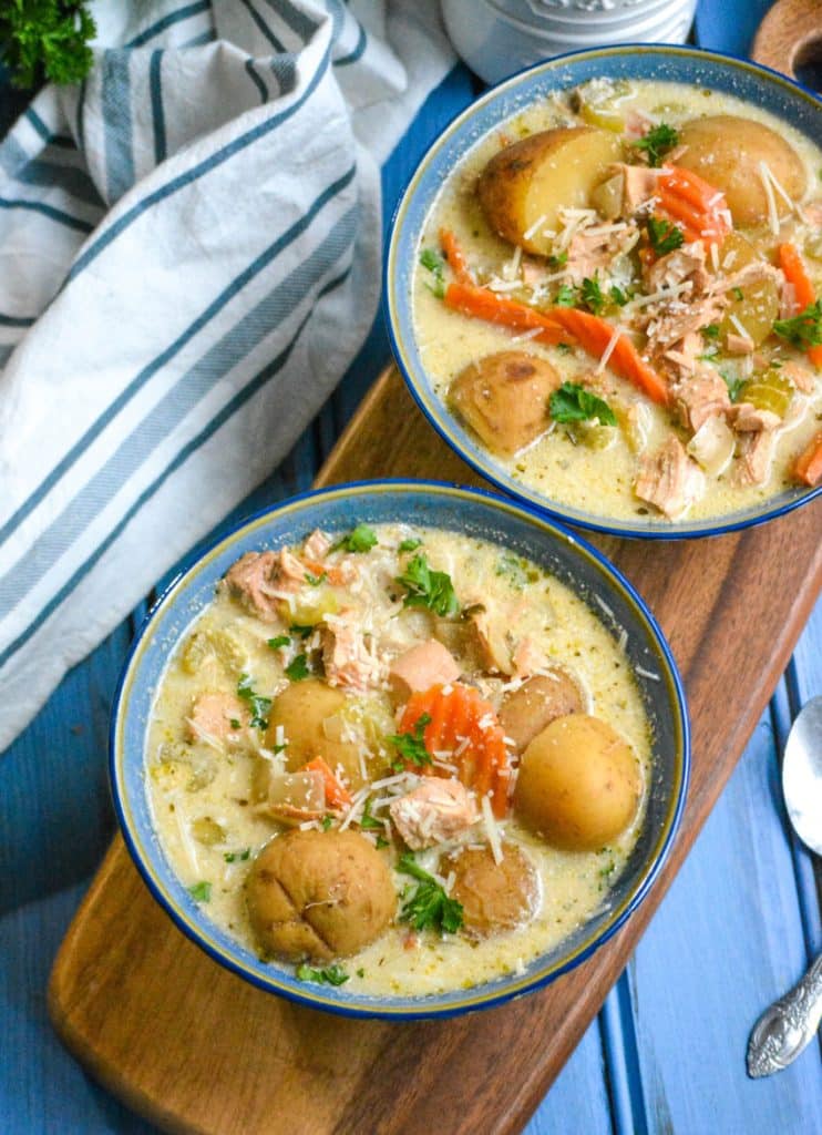 crockpot chicken stew in two blue bowls topped with shredded Parmesan cheese