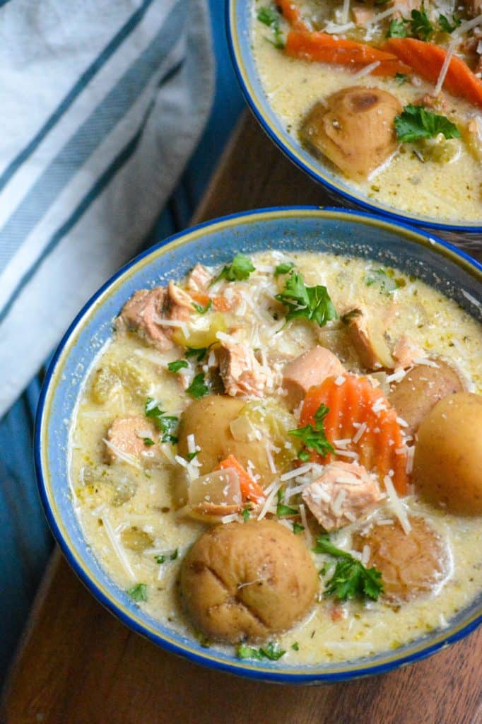 crockpot chicken stew in a blue bowl topped with shredded Parmesan cheese