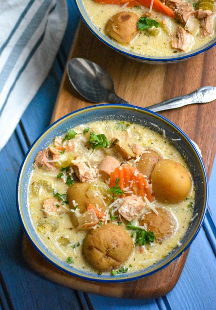 crockpot chicken stew in a blue bowl topped with shredded Parmesan cheese