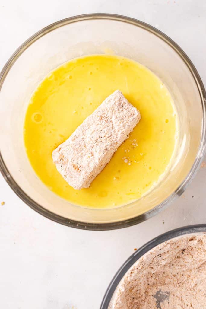 flour dredged cod in a bowl of beaten egg