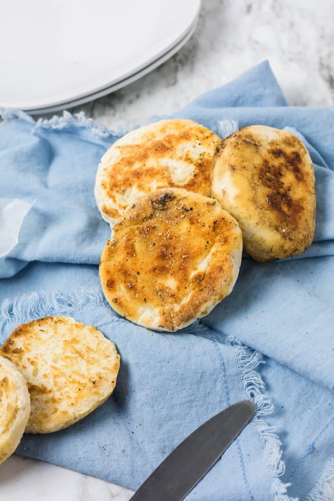 homemade english muffins on a blue cloth napkin
