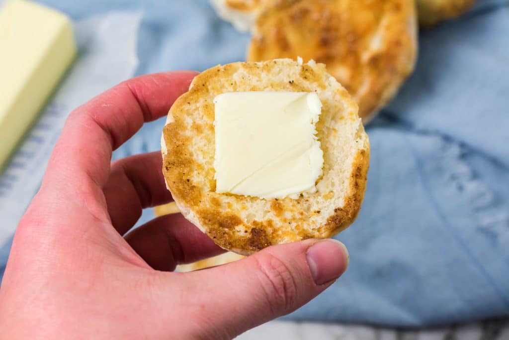 a hand holding up a golden brown, crispy buttered english muffin