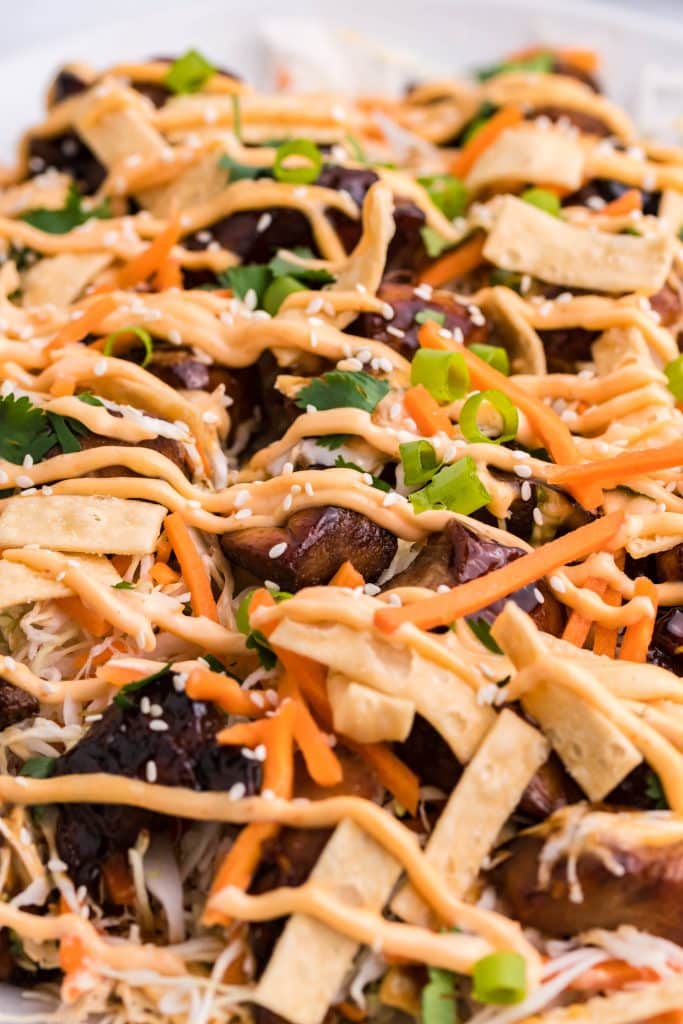 Asian chicken nachos shown drizzled with a sriracha cream sauce