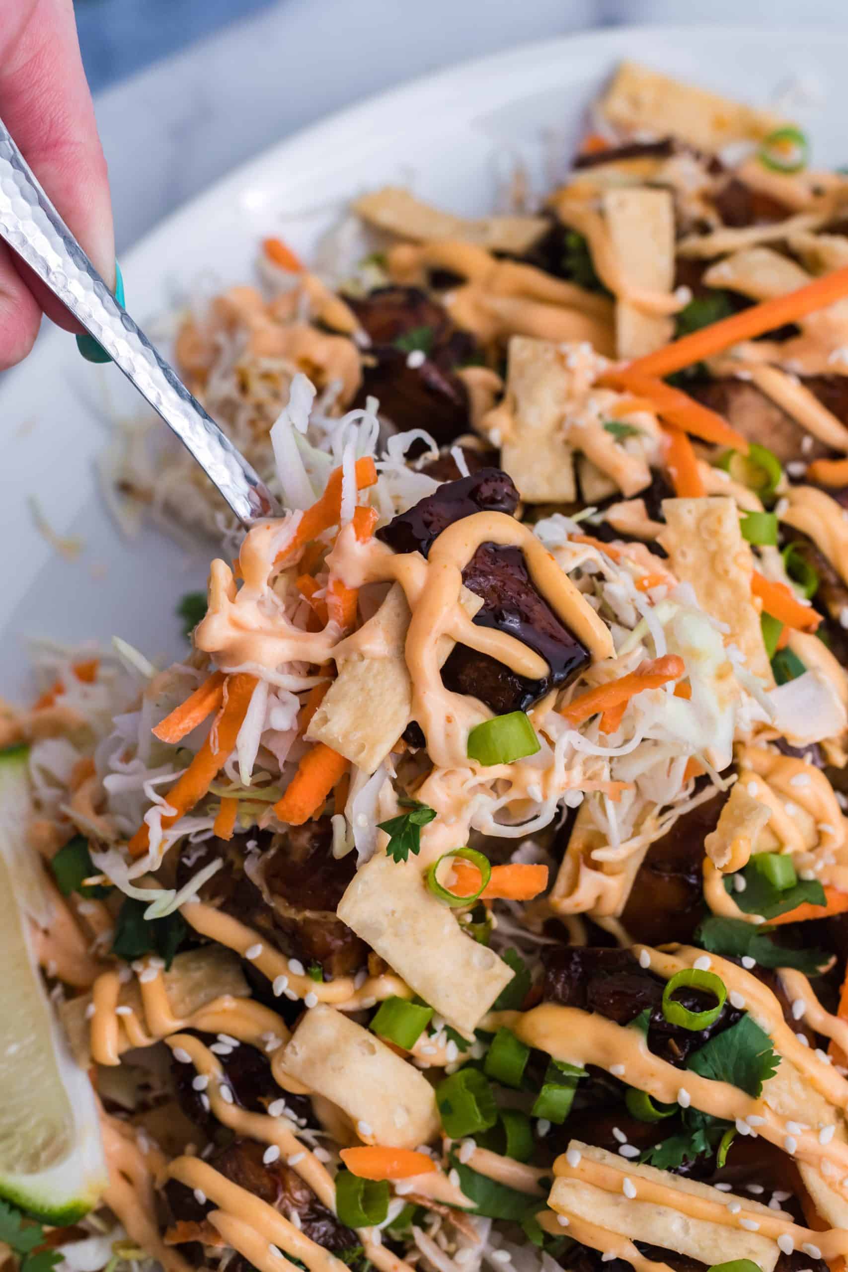 Asian Chicken Nachos a silver spoon lifting up a serving of Asian chicken nachos