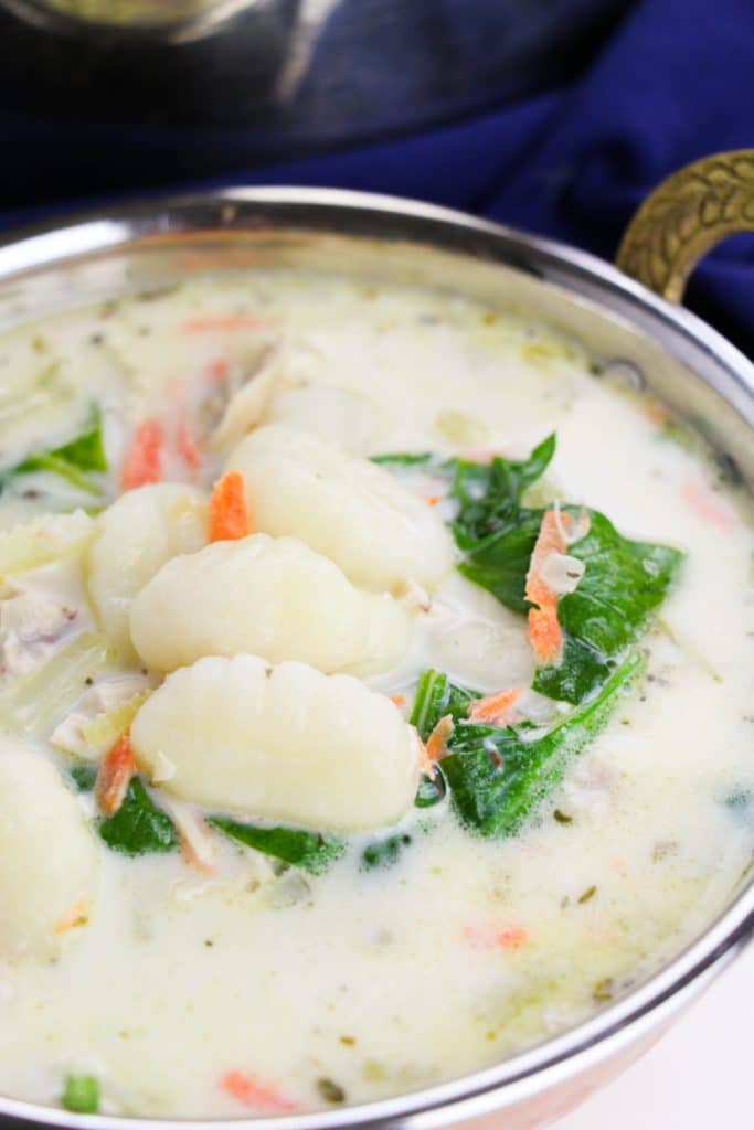 copycat olive garden chicken & gnocchi soup in a small bowl next to a silver pot