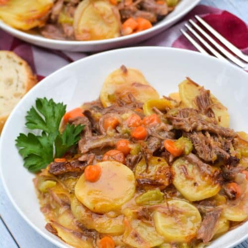 leftover pot roast casserole in two white bowls with sprigs of fresh parsley leaves on the side