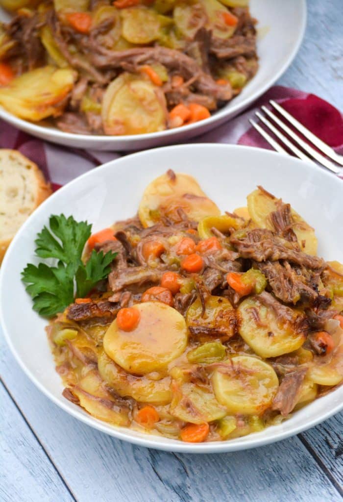 leftover pot roast casserole in two white bowls with sprigs of fresh parsley leaves on the side