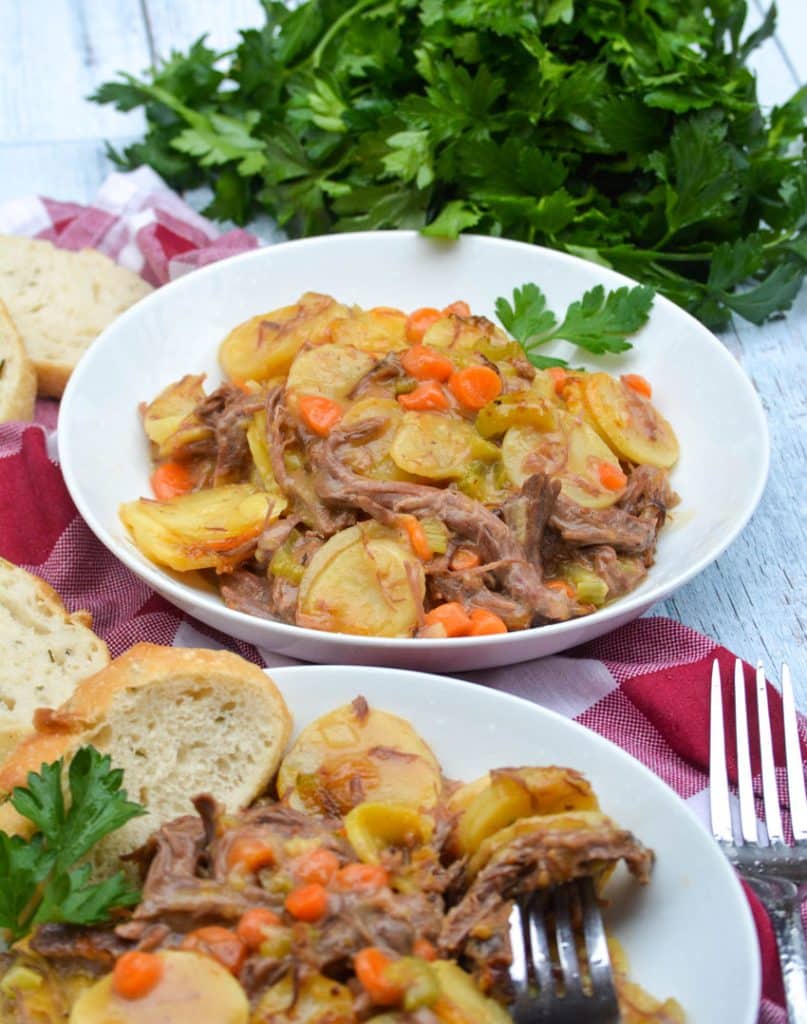 leftover pot roast casserole in two white bowls with sprigs of fresh parsley leaves on the side
