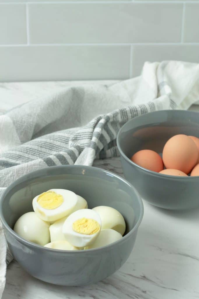 oven baked hard boiled eggs shown peeled & cut in half and piled in a gray bowl