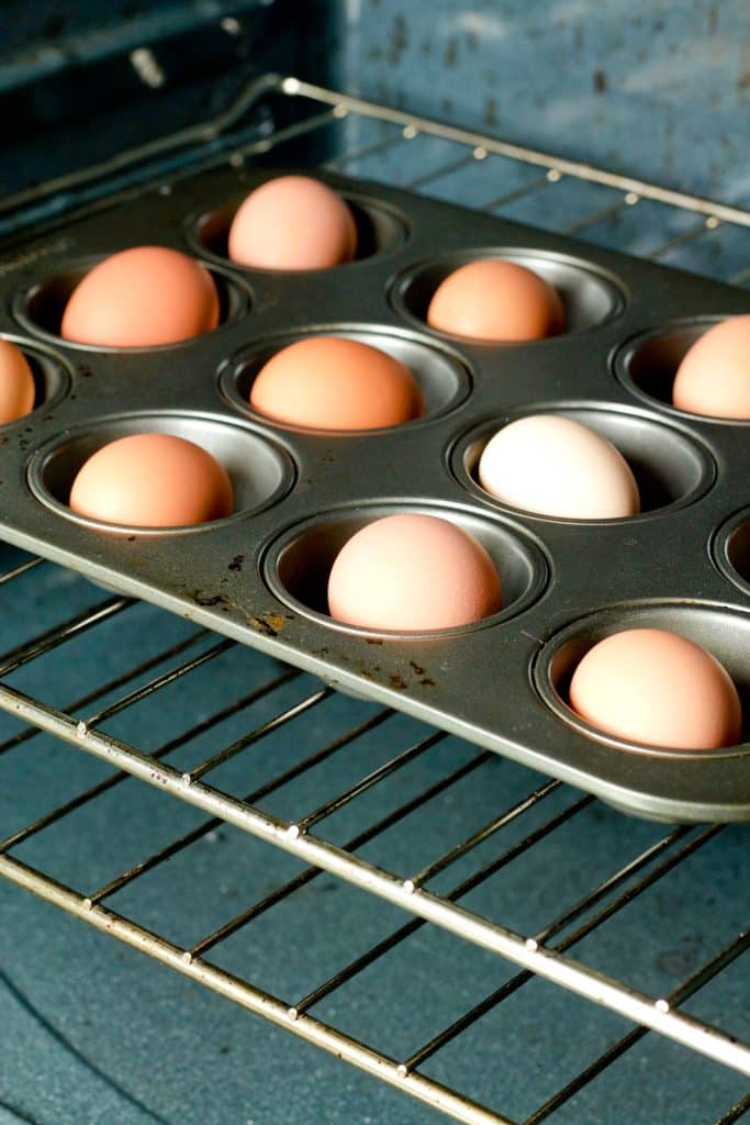 whole eggs in a muffin tin on a wrack inside an oven
