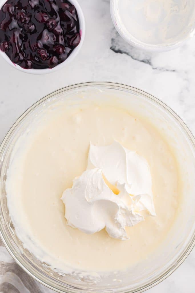 cool whip in a glass mixing bowl of cheesecake batter