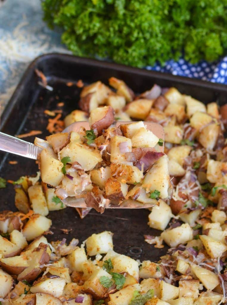 a silver spatula holding a serving of old bay roasted potatoes above a metal sheet pan