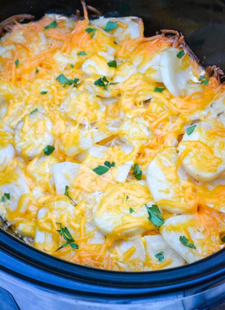 cheesy scalloped potatoes in the bowl of a black crockpot