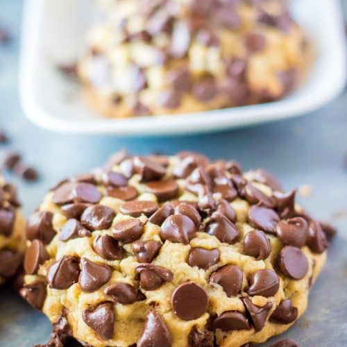 giant chocolate chip cookie in front of a white platter of cookies